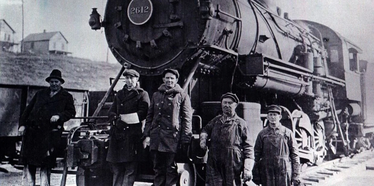 Five men standing beside a historic steam locomotive